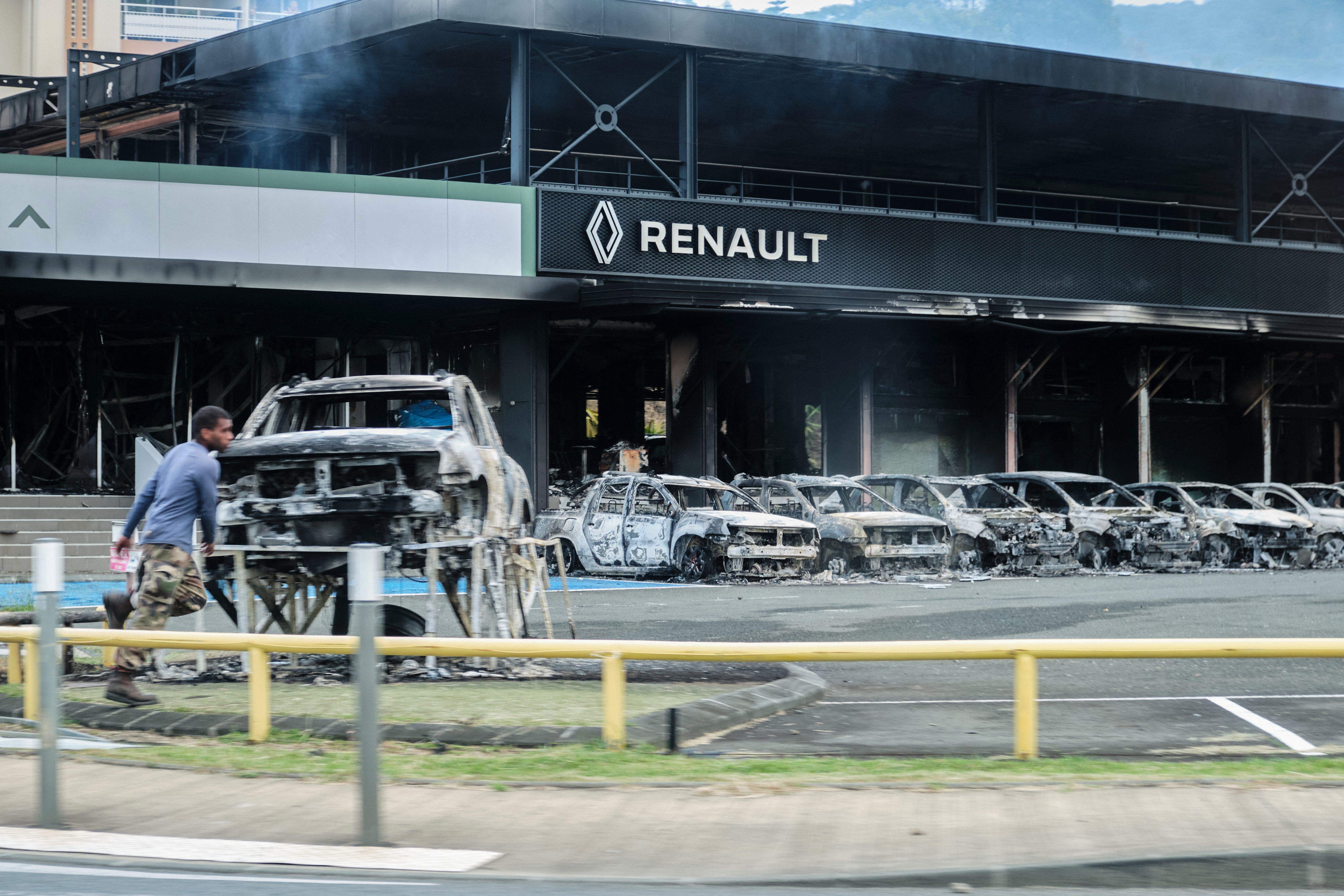 Mobil-mobil dan sebuah toko mobil Renault hangus terbakar di tengah-tengah unjuk rasa di Noumea, Kaledonia Baru, Selasa (14/5/2024). Pengunjuk rasa berdemo terkait rancangan undang-undang konstitusional yang bertujuan memperbesar jumlah pemilih untuk pemilu mendatang. (Foto: AFP/Theo Rouby)