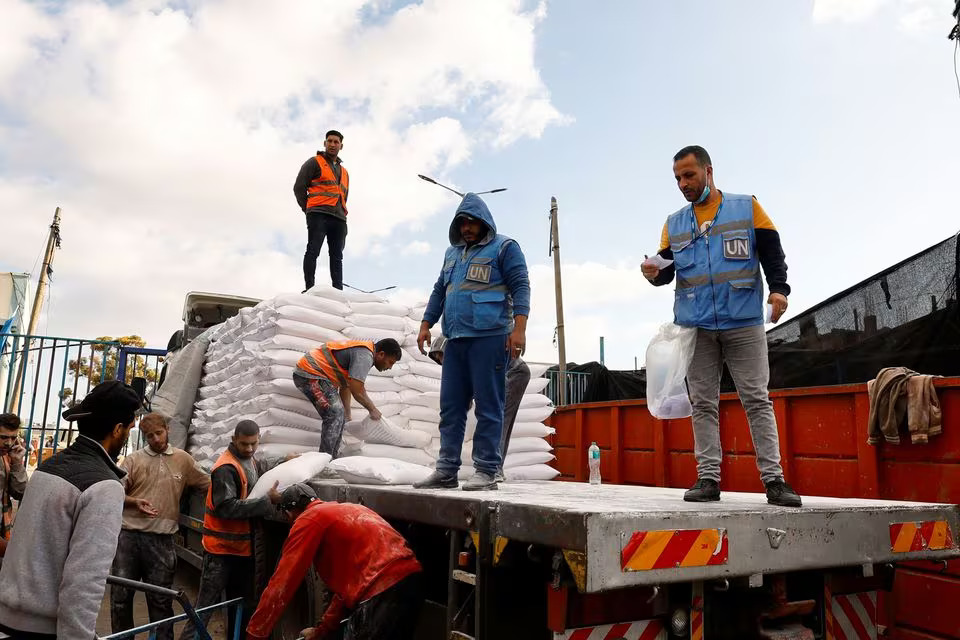Warga Palestina menerima kantong tepung yang didistribusikan oleh UNRWA di Rafah, di selatan Jalur Gaza 21 November 2023. (Foto: Reuters/Ibraheem Abu Mustafa)