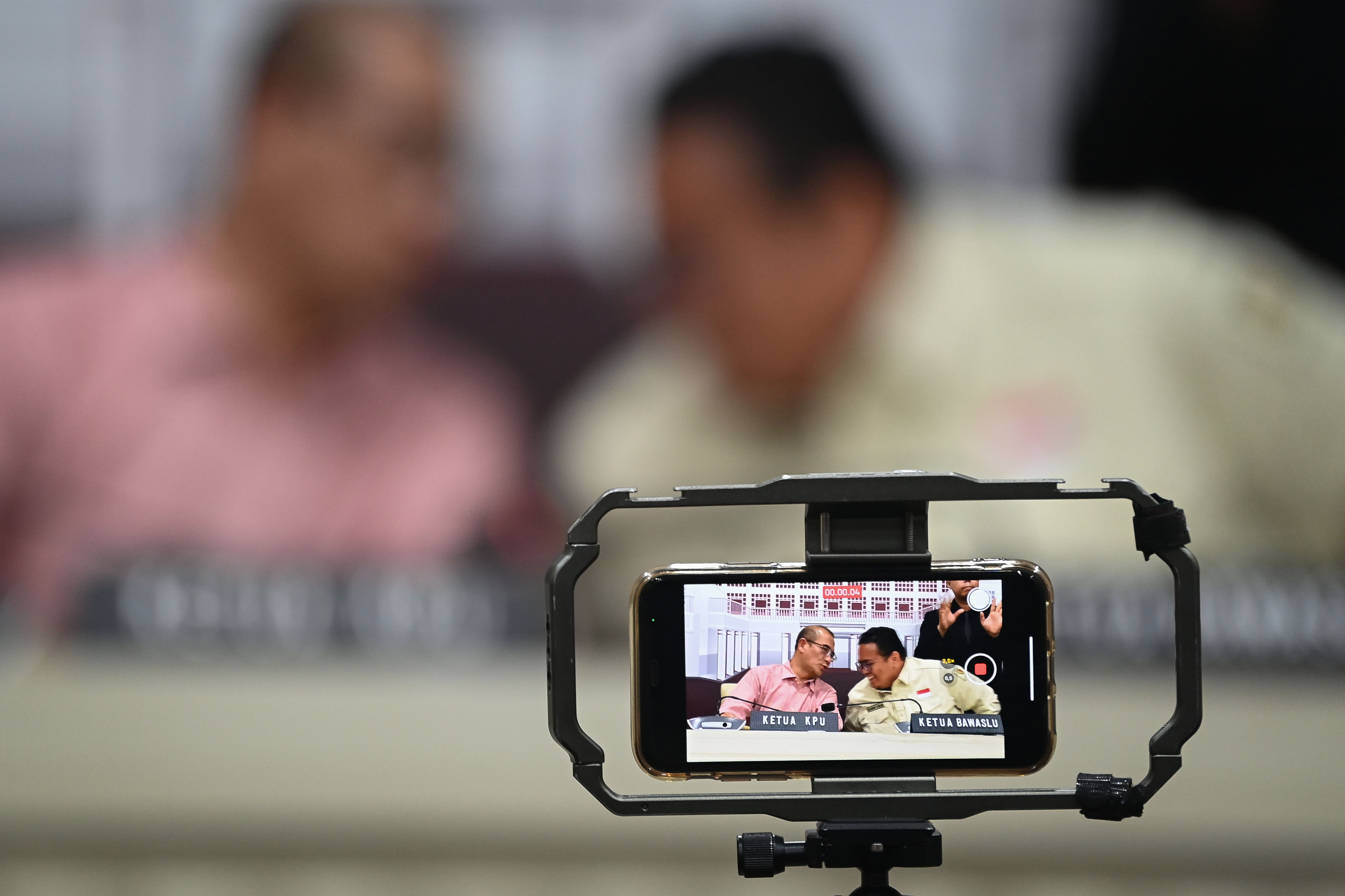  Kamera ponsel merekam Ketua KPU Hasyim Asy'ari (kiri) berbincang dengan Ketua Bawaslu Rahmat Bagja (kanan) di sela konferensi pers Pemilu 2024 di Kantor KPU, Jakarta, Kamis (15/02/2024). (Foto: Antara/Aditya Pradana Putra)