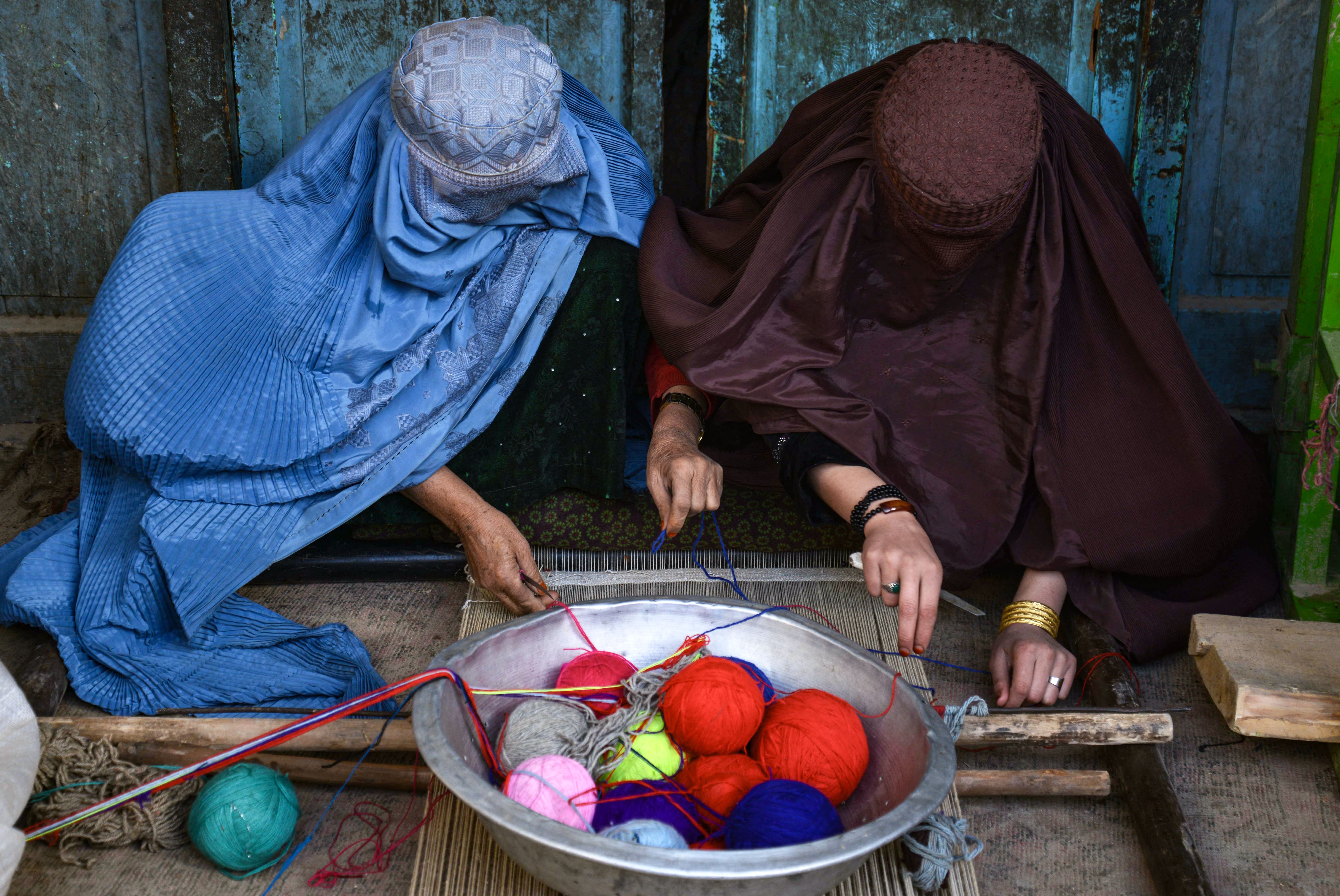 Dua perempuan menenun karpet di sebuah pabrik tradisional di Kandahar, Afganistan, Senin (19/02/2024). (Foto: AFP/Sanaullah Seiam)