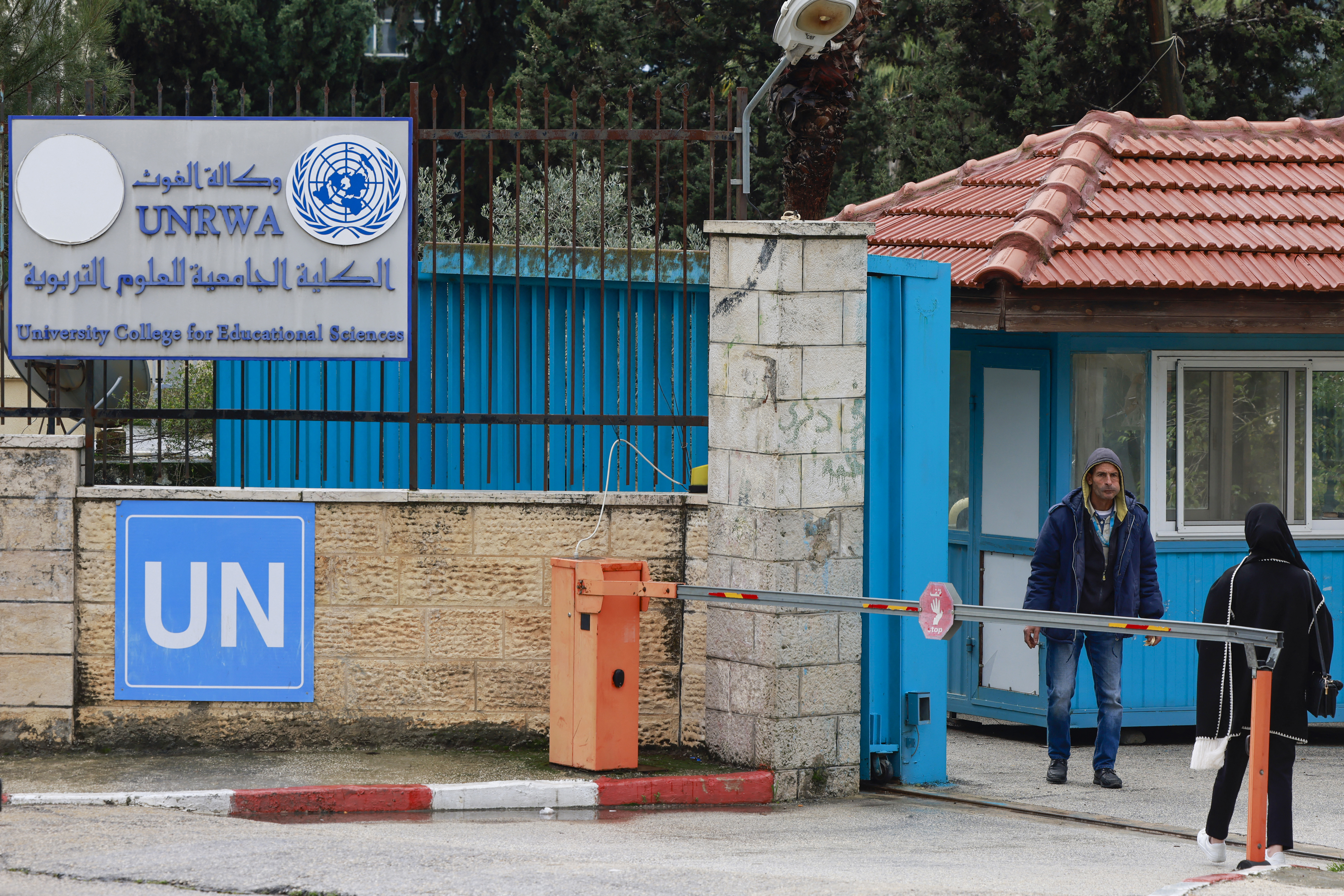 Warga Palestina berdiri di pintu masuk Universitas College for Educational Science (Perguruan Tinggi Ilmu Pendidikan) Ramallah yang dikelola UNRWA di Tepi Barat yang diduduki, Palestina pada Senin (29/01/2024). (Foto: AFP/Jaafar Ashtiyeh)
