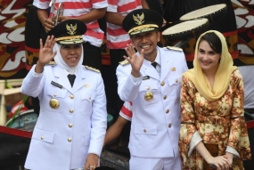 Gubernur Jawa Timur Khofifah Indar Parawansa (kiri) bersama Wakil Gubernur Jawa Timur Emil Elestianto Dardak (tengah) dan istrinya Arumi Bacshin (kanan) menyapa warga ketika diarak menuju Grahadi, Surabaya, Jawa Timur