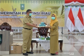 Vice-gouverneur van Riau Edy Natar Nasution (links) overhandigde symbolisch maskers die door de regering van Singapore waren geschonken aan het hoofd van het Riau Health Office Mimi Yuliani Nazi in Pekanbaru op dinsdag (8 december 2020). (ANTARA / HO-Diskominfotik Riau)