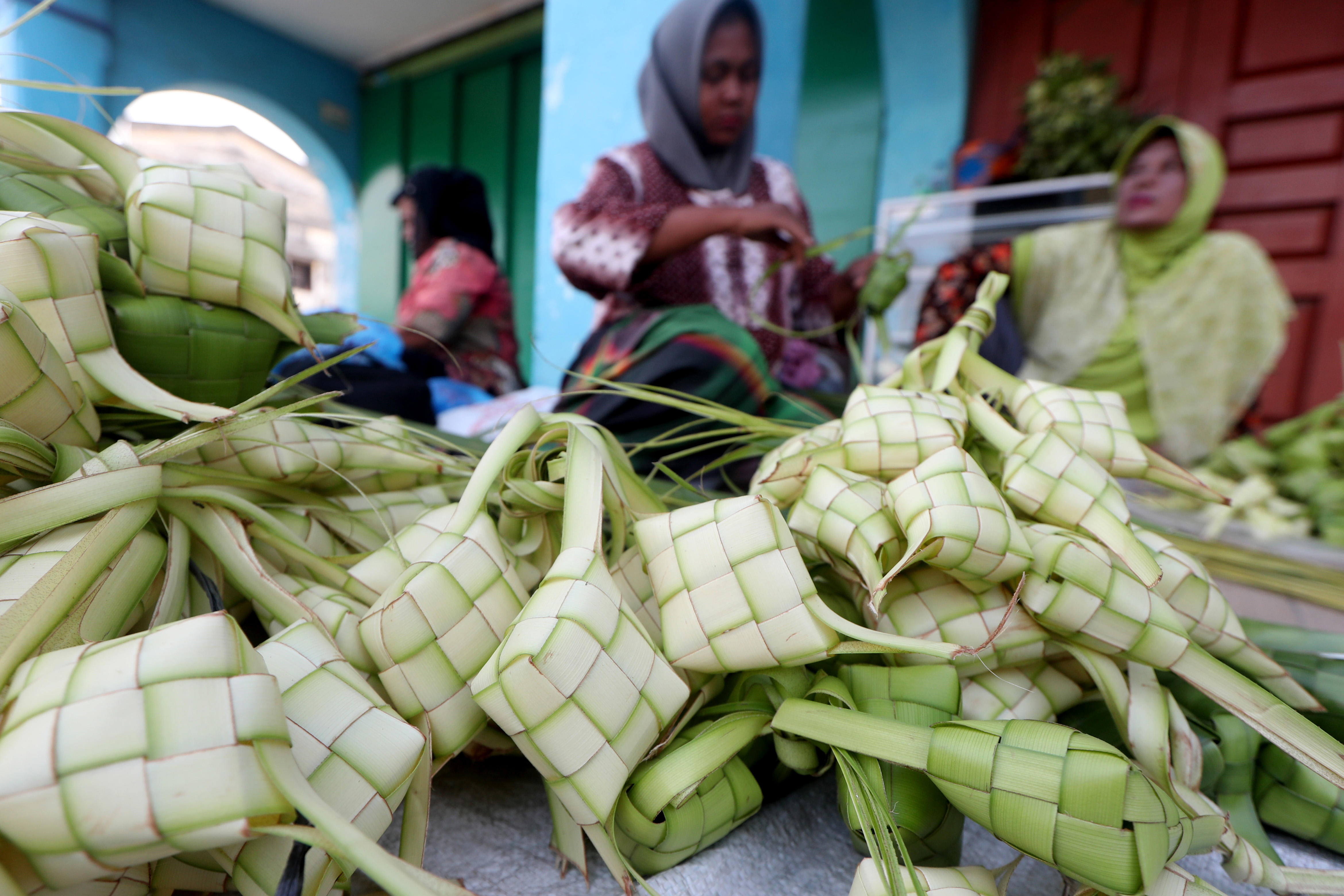 Warga membuat kulit ketupat untuk dijajakan di pasar tradisional Peunayong, Banda Aceh, Aceh, Selasa (9/4/2024). (Foto: ANTARA/Irwansyah Putra)