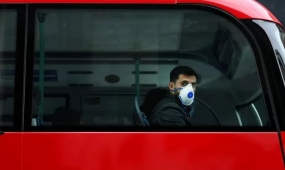 Seorang pria dengan masker wajah duduk di dalam bus, di tengah meningkatnya kasus virus COVID-19 di seluruh dunia, di pusat kota London, Inggris, Sabtu (14/3/2020). ANTARA FOTO/REUTERS/Dylan Martinez/WW/djo
