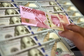 Petugas jasa penukaran valuta asing memeriksa lembaran mata uang rupiah dan dolar AS di Jakarta.