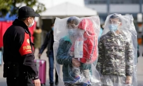 Sejumlah penumpang yang mengenakan masker dan ditutupi dengan kantong plastik berjalan di luar stasiun kereta api Shanghai di Shanghai, Cina, ketika negara itu dilanda wabah virus corona baru, Minggu (9/2/2020). ANTARA FOTO/ REUTERS/Aly Song/aww.