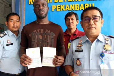 Arsip-WNA Liberia Harmon Hanson Daddyboy, saat proses deportasi berfoto dengan Kepala Rudenim Pekanbaru Junior M Sigalingging (kanan), di Pekanbaru, Riau, Selasa (21/5/2019).