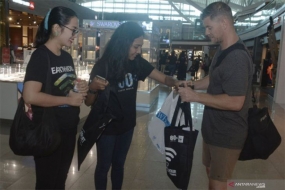 Relawan menukar kantong plastik yang digunakan pengguna jasa transportasi udara dengan tas kantong ramah lingkungan saat aksi &quot;rampok&quot; kantong plastik, di kawasan Terminal Internasional Bandara I Gusti Ngurah Rai, Bali, Senin (18/3/2019). Aksi tersebut untuk mengurangi penggunaan kantong plastik di kawasan bandara